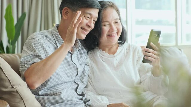 elderly couple social distancing communication at home grand father and grand mother sits on couch making videocall having pleasant conversation chatting with grown up children grandchildren