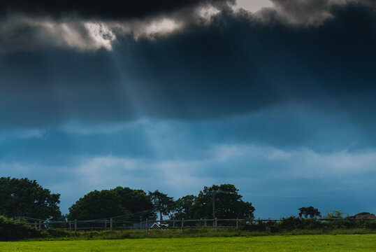 Image Showing A Bright Green Field With Streaks Of Light Coming Down From A Dark And Moody Sky. No People