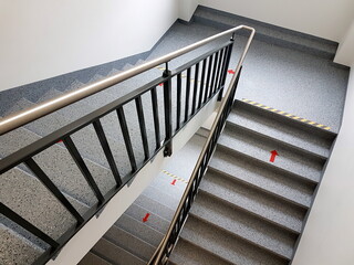Stairs in the stairwell of a multi storey house with a red directional arrow sign, top view