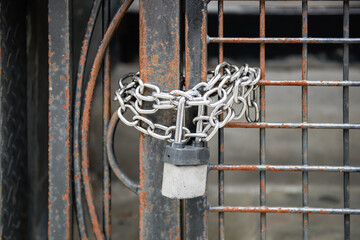 Chains with a padlock around a rusty gate.