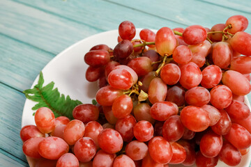 Red grapes in a white dish on the blue wooden floor on the view on the right.