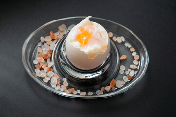 soft-boiled chicken egg in a stand on a black background.