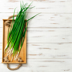A bunch of green onions on a light wooden background.