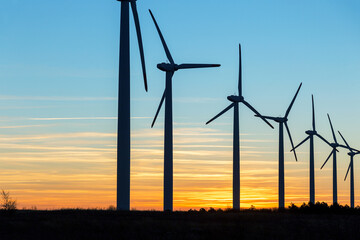 Wind Turbines at Dusk. Landscape sunset with windmills. Renewal source of electricity. Wind turbines field new technology for clean energy on mountain, sunset view with colorful twilight on sky