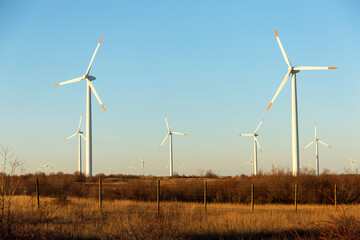 Fototapeta premium Wind Turbines at Dusk. Landscape sunset with windmills. Renewal source of electricity. Wind turbines field new technology for clean energy on mountain, sunset view with colorful twilight on sky