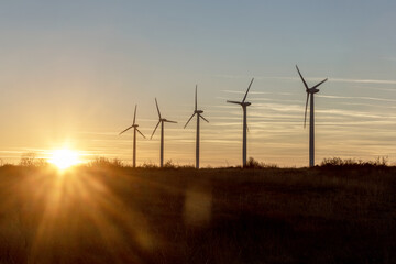 Obraz premium Wind Turbines at Dusk. Landscape sunset with windmills. Renewal source of electricity. Wind turbines field new technology for clean energy on mountain, sunset view with colorful twilight on sky