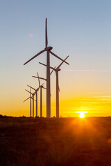 Obraz premium Wind Turbines at Dusk. Landscape sunset with windmills. Renewal source of electricity. Wind turbines field new technology for clean energy on mountain, sunset view with colorful twilight on sky