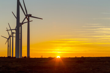 Wind Turbines at Dusk. Landscape sunset with windmills. Renewal source of electricity. Wind turbines field new technology for clean energy on mountain, sunset view with colorful twilight on sky