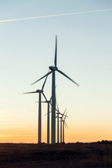 Wind Turbines at Dusk. Landscape sunset with windmills. Renewal source of electricity. Wind turbines field new technology for clean energy on mountain, sunset view with colorful twilight on sky