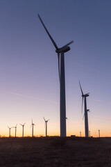 Wind Turbines at Dusk. Landscape sunset with windmills. Renewal source of electricity. Wind turbines field new technology for clean energy on mountain, sunset view with colorful twilight on sky