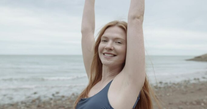 Pretty redhead woman in sea dancing with hands in air enjoying freedom and nature