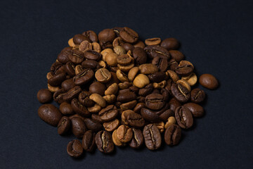 Coffee beans on a black background. Coffee beans of different roasts in one pile.