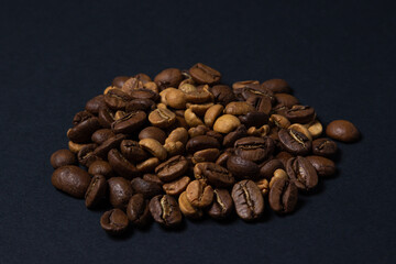 Coffee beans on a black background. Coffee beans of different roasts in one pile.