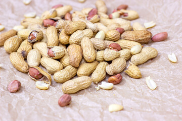 Raw unpeeled peanut nuts in nutshell on light paper background.