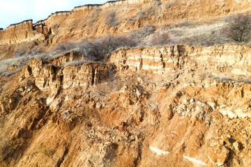 Panoramic view bird's-eye view. Mountain landslide in an environmentally hazardous area. Large cracks in the ground, the descent of layers of dirt road. Deadly risk of collapse of the soil on coast