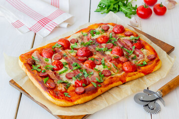 Pizza with bacon, sausage, mozzarella, tomatoes and basil. Italian cuisine. Recipe.