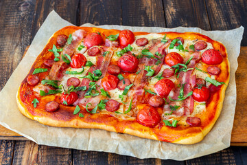 Pizza with bacon, sausage, mozzarella, tomatoes and basil. Italian cuisine. Recipe.