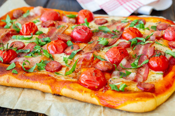 Pizza with bacon, sausage, mozzarella, tomatoes and basil. Italian cuisine. Recipe.