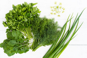 Fresh dill, parsley and onion arugula on a white wooden background