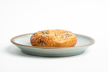 A Freshly Baked Single Bagel On A Ceramic Plate