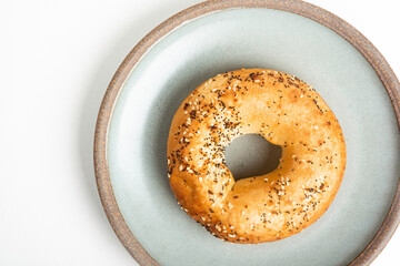 A Freshly Baked Single Bagel On A Ceramic Plate