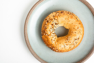 A Freshly Baked Single Bagel On A Ceramic Plate