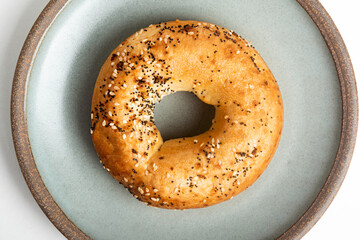 A Freshly Baked Single Bagel On A Ceramic Plate