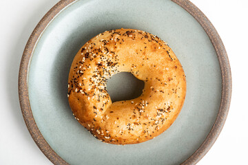 A Freshly Baked Single Bagel On A Ceramic Plate