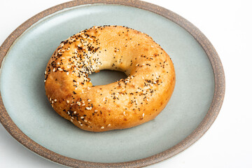 A Freshly Baked Single Bagel On A Ceramic Plate