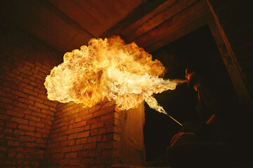 Male fakir blowing out fire in an abandoned building at night. Fire performer blowing out fire...