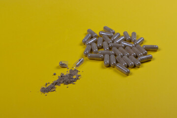 Green lipped mussels extract pills on a yellow background and open capsule with extract powder. Biologically active supplements
