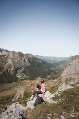 Fototapeta premium Young woman sitting on the rock watching the beautiful landscape of Somiedo natural park in Asturias, Spain, mountain valley