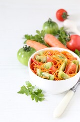 Korean vegetable salad of red and green tomatoes with carrots, garlic and parsley in a bowl  on a white background