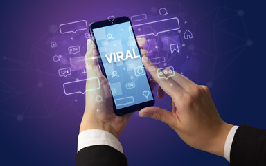 Female hand typing on smartphone with VIRAL inscription, social media concept