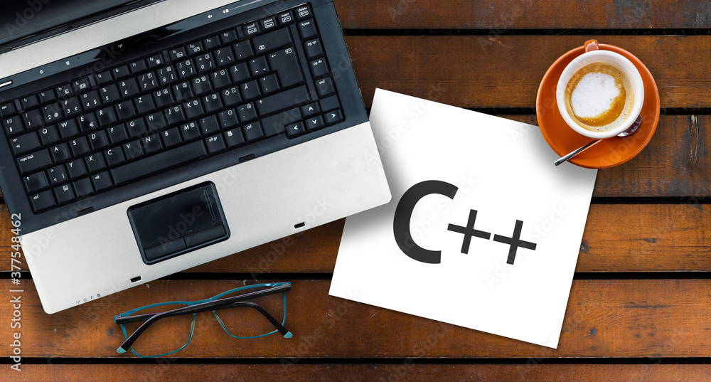 Poster c++ programming language. paper width word c++ and laptop, glasses and coffee on wooden table