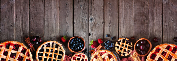 Selection of homemade autumn fruit pies. Top view border over a dark wood banner background with copy space. Cherry, strawberry and blueberry. - obrazy, fototapety, plakaty