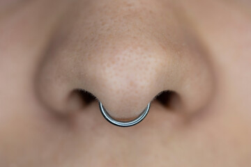 Nose piercing septum. Beautiful piercing jewelry. Macro shot. Selective focus. - obrazy, fototapety, plakaty