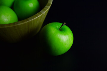 Three green apples are placed on a black background
