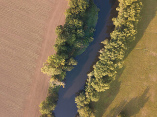 Top view of the river with turns of meanders and green forests in bright sunlight. Creek in the park among the trees. Aerial drone view. Summer or autumn time.
Stream surrounded by green forest.