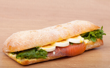 Real sandwich with smoked salmon, eggs and green on a wooden background