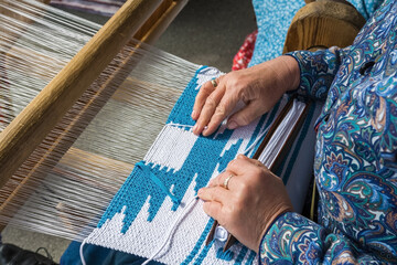 Woman hand weaving on manual loom. Fabric handmade.  The process of fabric weaving in vintage weaver machine.