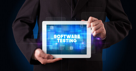 Young business person working on tablet and shows the inscription: SOFTWARE TESTING