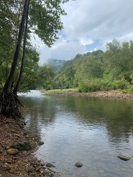 Looking down the Buffalo National River from the Steele Creek access in Buffalo, Arkansas, on a foggy, rainy day, with clouds in the sky. 