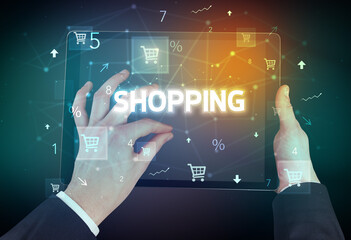 Close-up of a hand holding tablet with SHOPPING inscription, online shopping concept