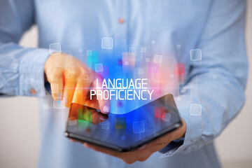 Young man holding a foldable smartphone with LANGUAGE PROFICIENCY inscription, educational concept