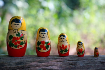 Nesting dolls stand in a row on a colored background.