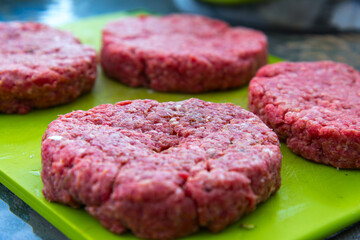 Raw beef burgers close up on a chopping board
