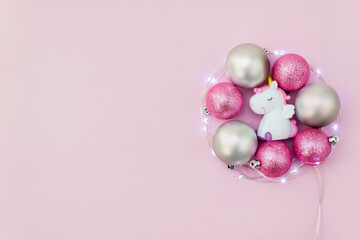 Christmas tree balls and unicorn toy surrounded by light garland. New year decoration. Copy space