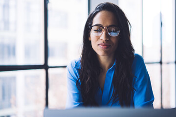 Professional black businesswoman in glasses working on laptop at office