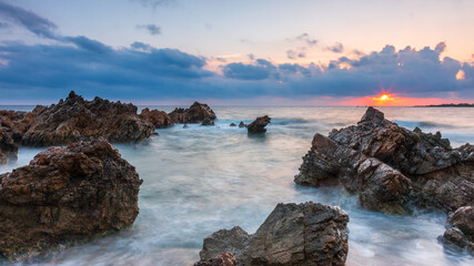 Puesta de sol en la costa de Menorca con mar azul 